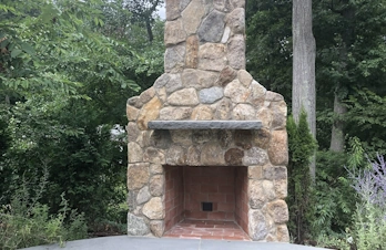 Charming outdoor kitchen in Concord, Massachusetts, with a brick chimney, bar, and smoker, ideal for cooking and socializing